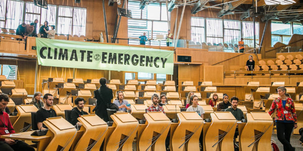 XR Scotland protestors in Scottish Parliament hanging up banner saying Climate Emergency
